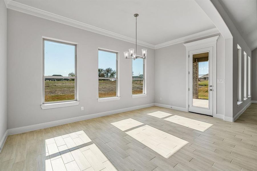 Unfurnished dining area featuring crown molding, wood tiled floors, and a chandelier