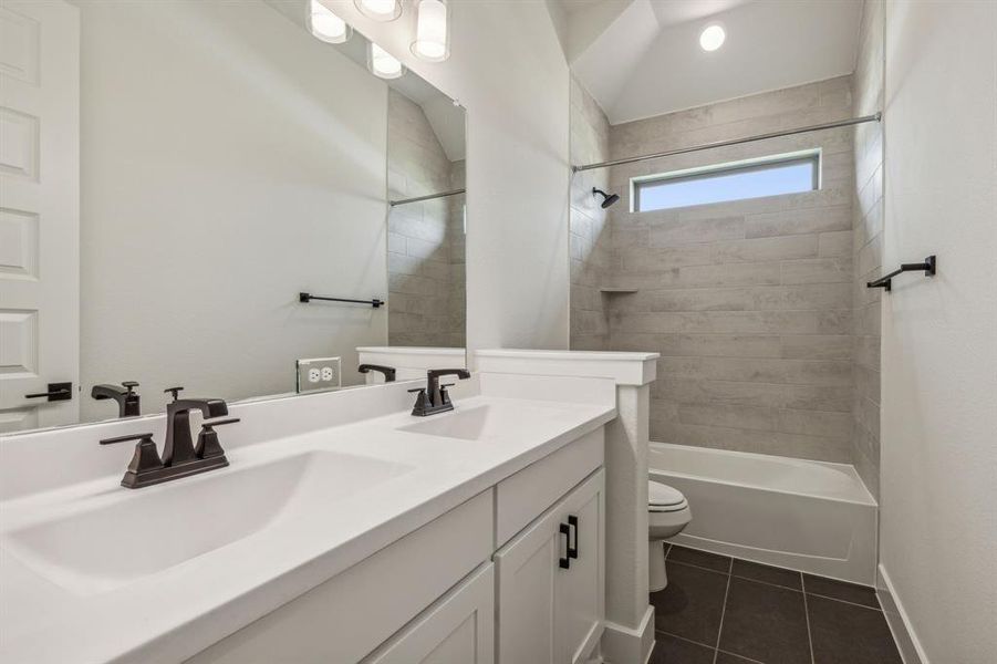 Full bathroom with vanity, toilet, tile patterned floors, and tiled shower / bath