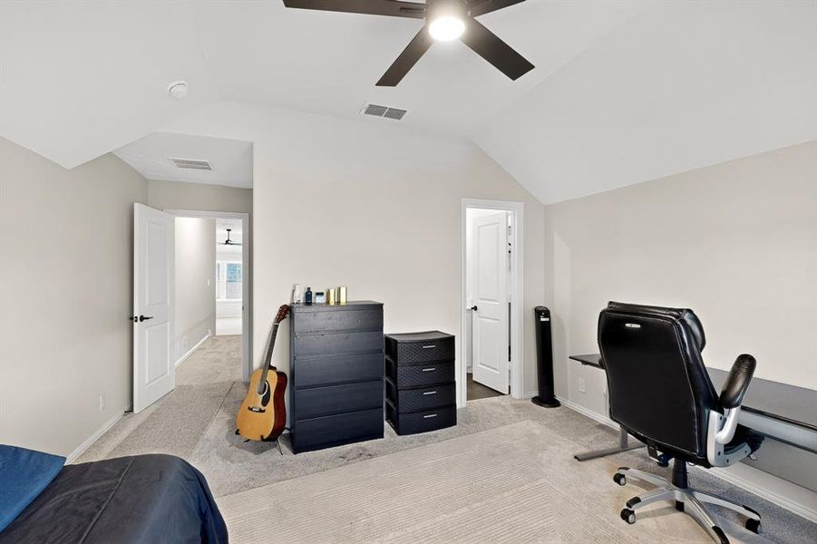 Bedroom with light colored carpet, lofted ceiling, ceiling fan, and a desk Bedroom with light colored carpet, lofted ceiling, ceiling fan, and a desk