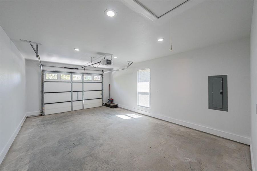 Garage featuring electric panel, recessed lighting, and a garage door opener Garage featuring electric panel, recessed lighting, and a garage door opener