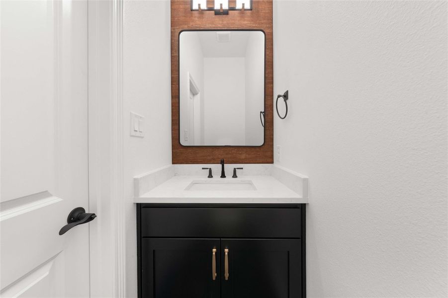 A refined bathroom featuring a contemporary vanity with sleek hardware, a modern mirror, and overhead lighting. A refined bathroom featuring a contemporary vanity with sleek hardware, a modern mirror, and overhead lighting.
