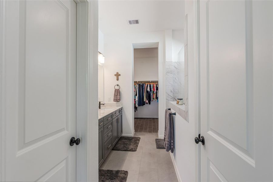Spacious bathroom with dual sinks, elegant cabinetry, and a walk-in closet for ample storage. Separate toilet room and walk in linen closet.