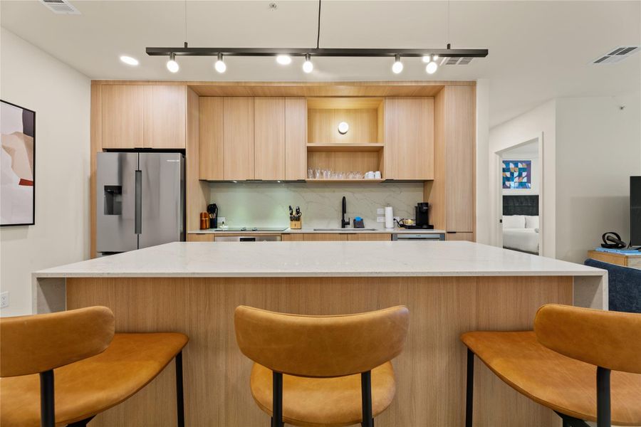 A spacious preparation island with integrated dining space anchors this modern cooking area.