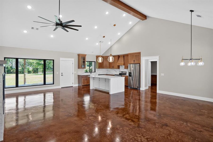 Open-concept living space featuring wood-finish flooring, a vaulted ceiling with exposed beam, and recessed lighting Open-concept living space featuring wood-finish flooring, a vaulted ceiling with exposed beam, and recessed lighting