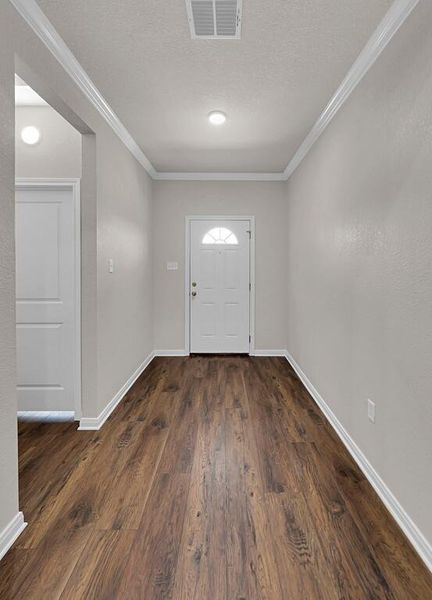 Entrance foyer with ornamental molding, dark wood finished floors, and a textured ceiling