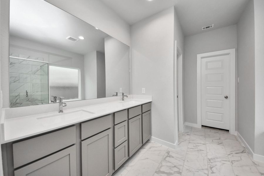 Indulge in a spa-like retreat within the confines of this primary bathroom. Delight in a spacious walk-in shower enveloped in stylish tile surround, unwind in a separate garden tub adorned with custom detailing. Sample photo of completed home with similar floor plan. Actual colors and selections may vary.