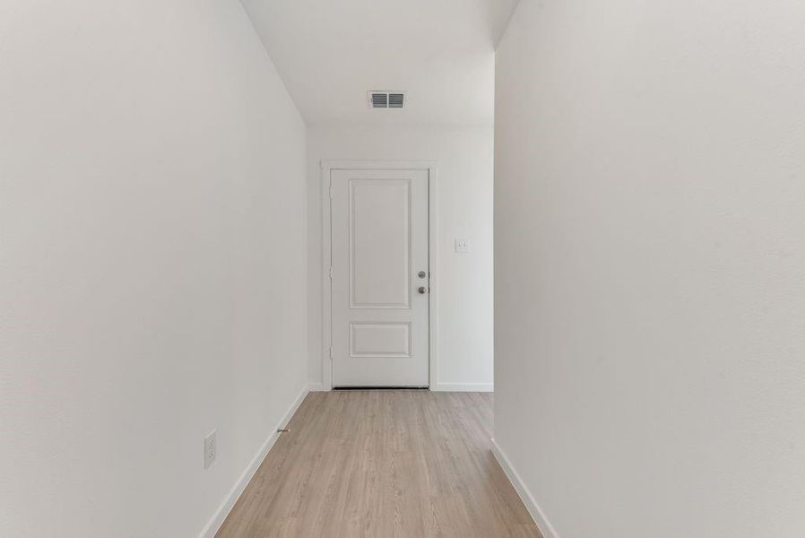 Corridor with visible vents, light wood-style flooring, and baseboards