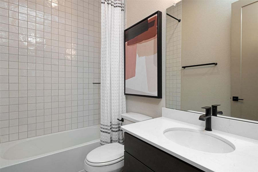 The secondary bath features tile flooring, white cabinetry and light countertops and a shower/tub combo. Perfect for accommodating any visiting family and friends.