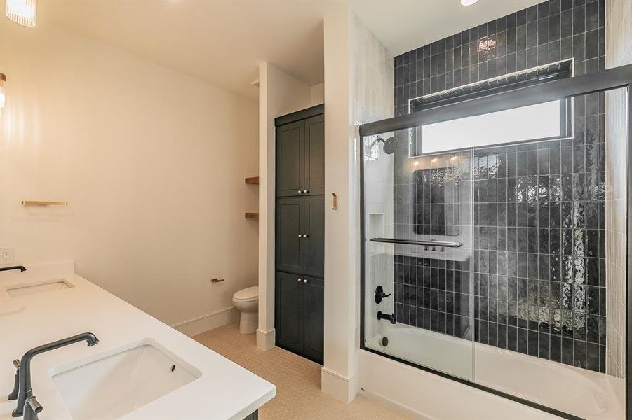 Bathroom featuring shower / bath combination with glass door, double vanity, and a closet