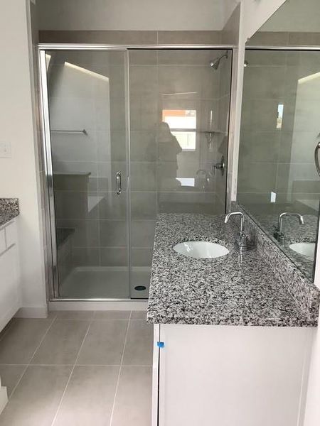 Bathroom with tile patterned floors, vanity, and walk in shower