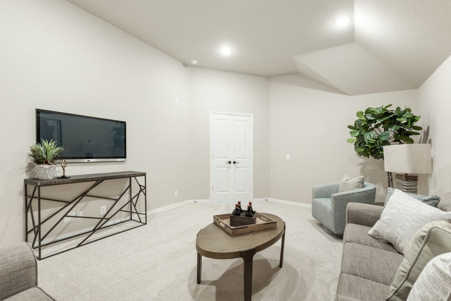Living room with gray sofa, wall-mounted TV, round coffee table, and light carpet