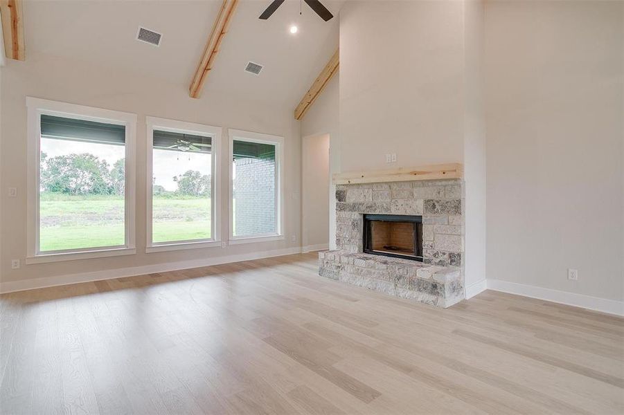 Unfurnished living room featuring light hardwood / wood-style floors, a wealth of natural light, high vaulted ceiling, and ceiling fan