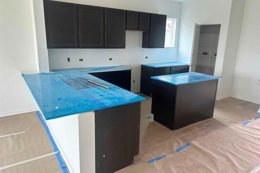 Kitchen featuring dark cabinets, tasteful backsplash, and a peninsula