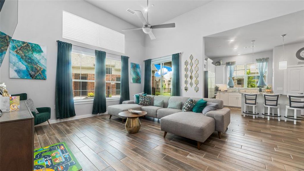 Living room featuring high vaulted ceiling, ceiling fan, a healthy amount of sunlight, and dark wood-type flooring