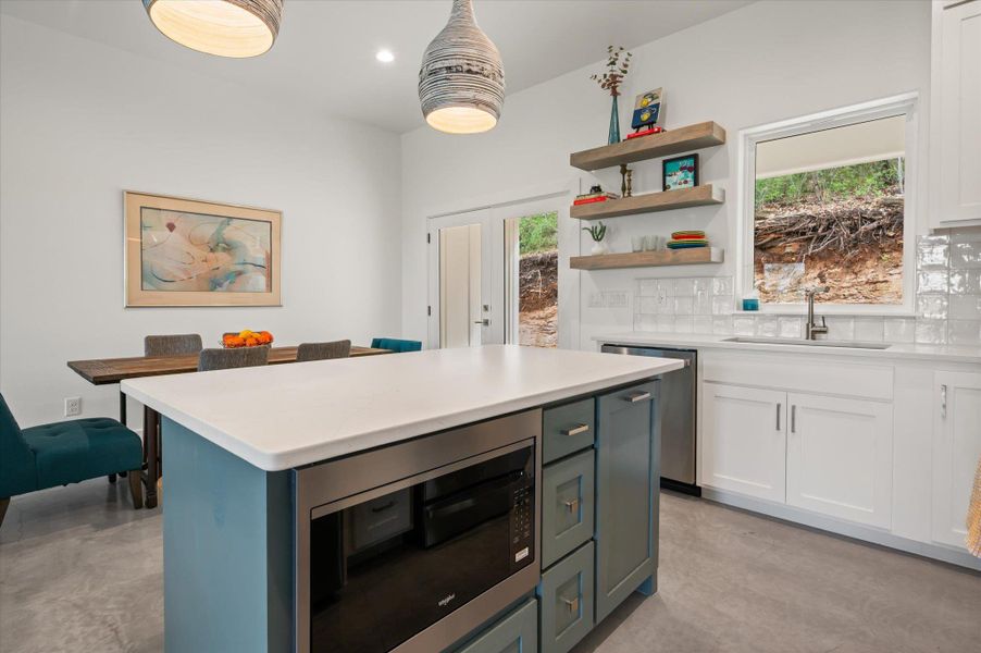 Island with custom paint, built in microwave and oversized pull out garbage and recycling bin.