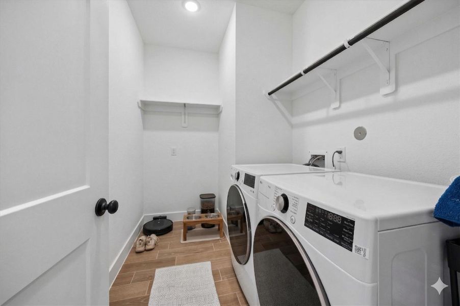 Functional laundry room featuring durable wood-plank-look tile flooring and overhead shelving for storage. This space is designed for convenience and accommodates full-sized appliances while matching the home's modern, high-end aesthetic. Functional laundry room featuring durable wood-plank-look tile flooring and overhead shelving for storage. This space is designed for convenience and accommodates full-sized appliances while matching the home's modern, high-end aesthetic.