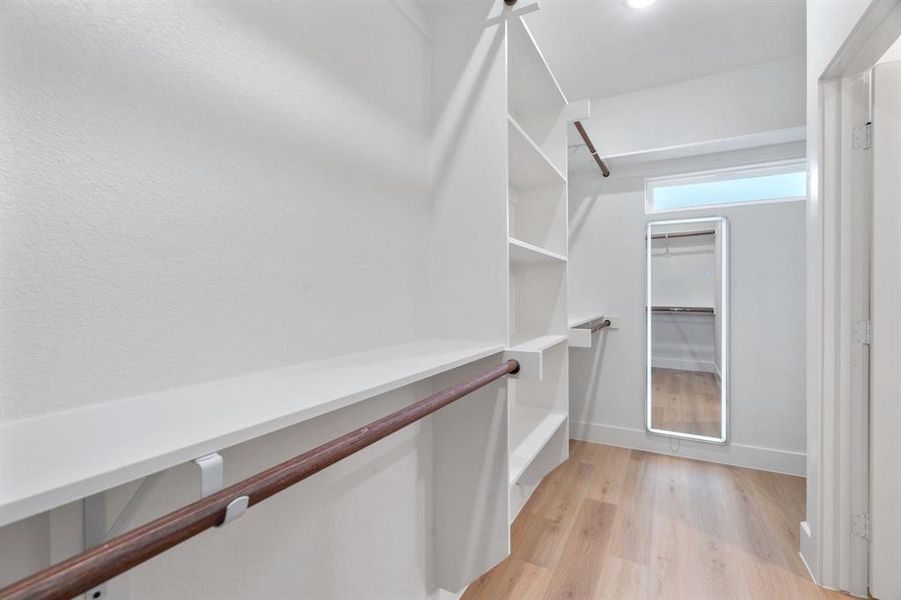 Walk in closet with light wood-style flooring