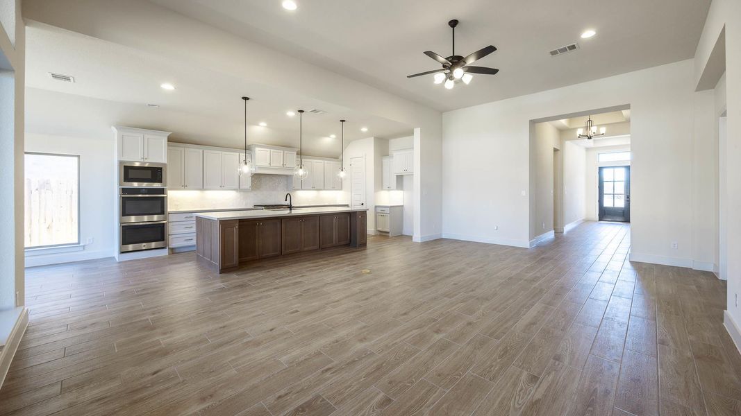Kitchen featuring open floor plan, white cabinetry, recessed lighting, backsplash, and light countertops