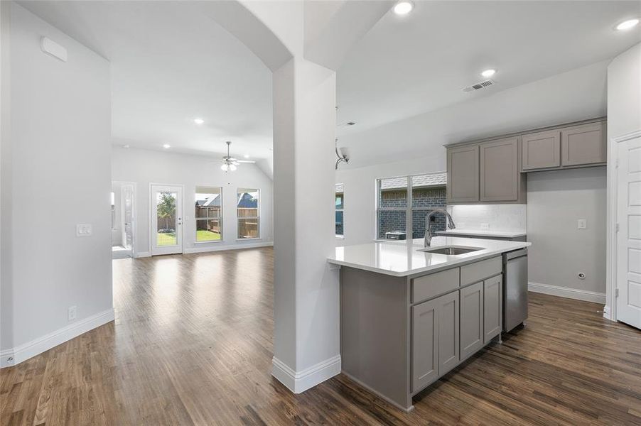 Kitchen with gray cabinetry, dark wood-type flooring, recessed lighting, arched walkways, and light stone counters