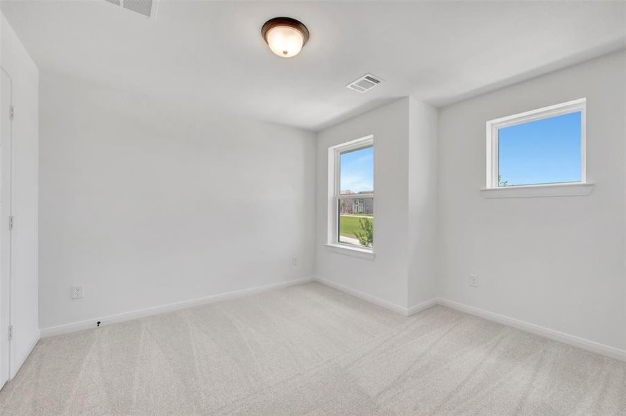Interior room featuring two windows, light gray carpet, white walls, and a ceiling-mounted light fixture