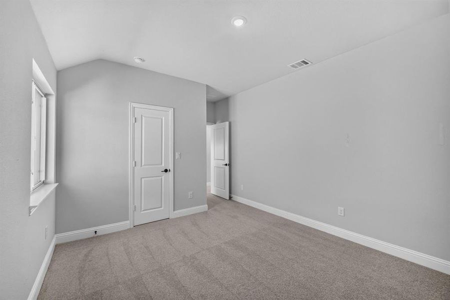 Carpeted room with vaulted ceiling and recessed lighting