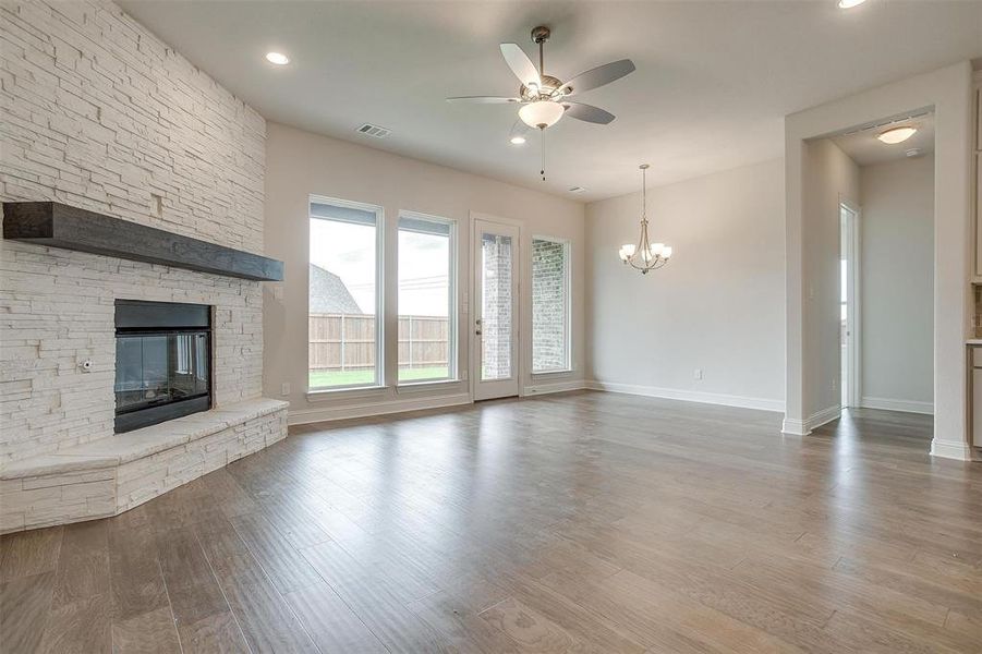 Unfurnished living room featuring ceiling fan with notable chandelier, hardwood / wood-style flooring, and a fireplace