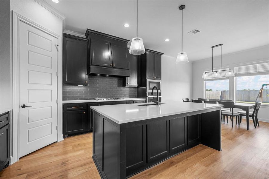 Kitchen with dark cabinetry, decorative backsplash, pendant lighting, recessed lighting, and crown molding Kitchen with dark cabinetry, decorative backsplash, pendant lighting, recessed lighting, and crown molding