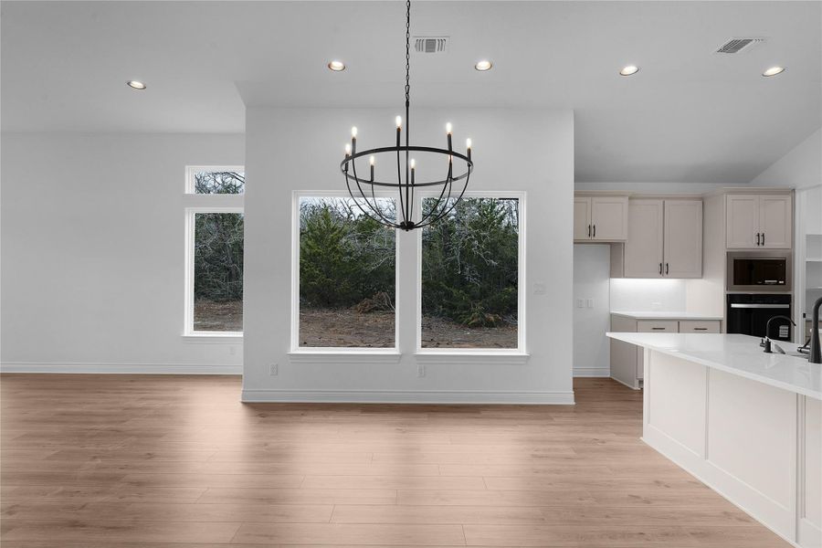Unfurnished dining area featuring hanging lights and light wood finished floors