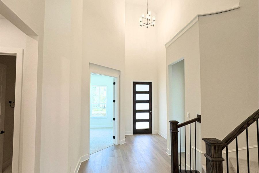 An inviting entryway boasts soaring ceilings, wood-look flooring, and a modern multi-lite glass front door. An inviting entryway boasts soaring ceilings, wood-look flooring, and a modern multi-lite glass front door.