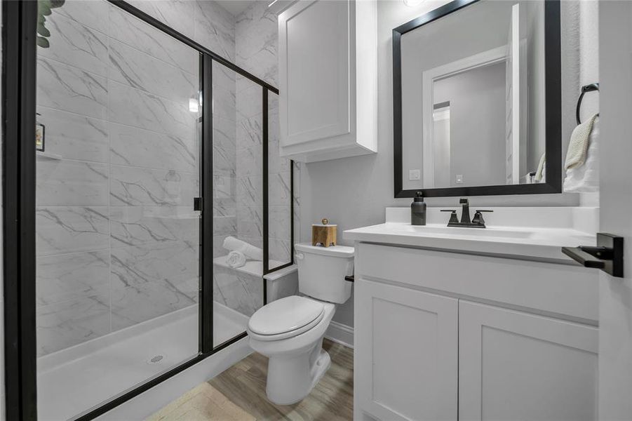 Full bath with a marble finish shower, vanity, and light wood-style floors Full bath with a marble finish shower, vanity, and light wood-style floors