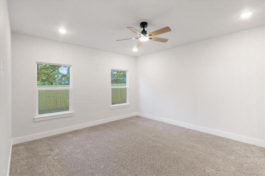 Carpeted spare room with a healthy amount of sunlight and ceiling fan