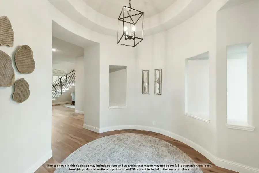 Foyer with round tray ceiling, black geometric chandelier, hardwood floors, and staircase visible in background. Foyer with round tray ceiling, black geometric chandelier, hardwood floors, and staircase visible in background.