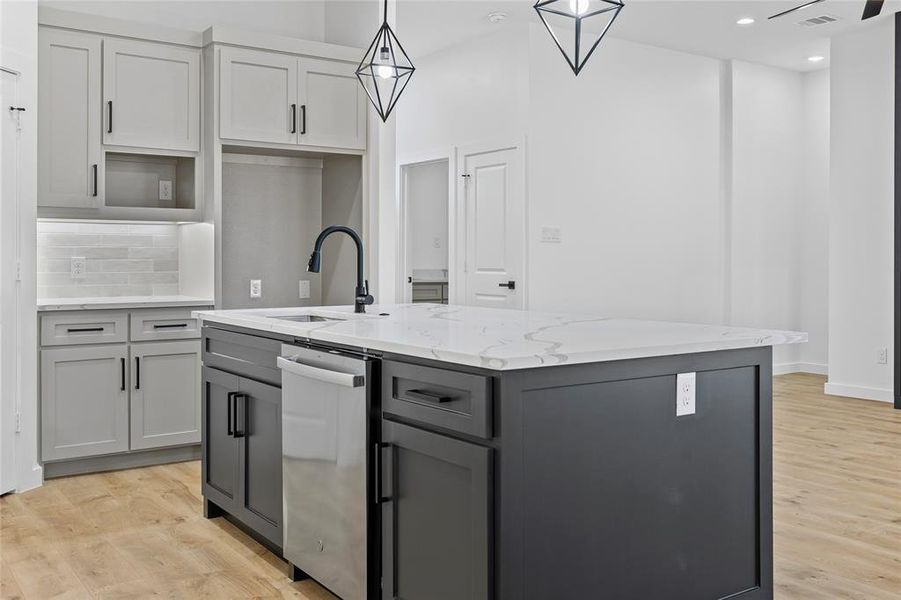 Kitchen featuring light wood finished floors, gray cabinetry, backsplash, and a sink