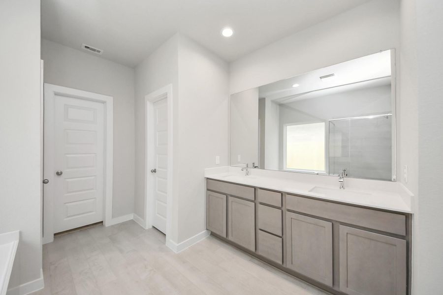 Elevate your daily routine at the elegant vanity, now equipped with double sinks, light countertops, modern hardware, and beautiful recessed lights. Sample photo of completed home with similar floor plan. Actual colors and selections may vary.
