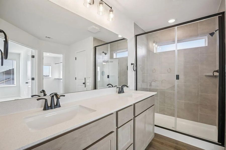 A well-appointed primary bathroom showcases dual vanities, contemporary fixtures, and a spacious glass-enclosed shower. A well-appointed primary bathroom showcases dual vanities, contemporary fixtures, and a spacious glass-enclosed shower.