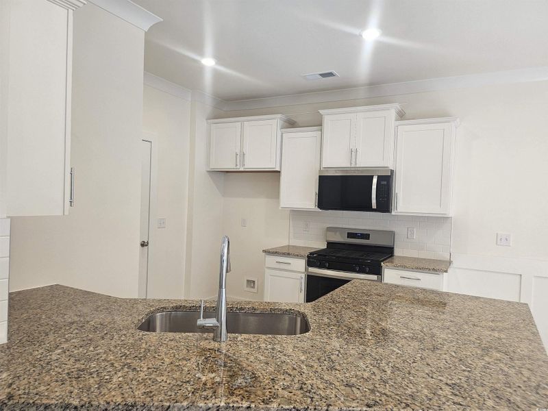 Kitchen with stainless steel appliances, a peninsula, white cabinets, and dark stone counters Kitchen with stainless steel appliances, a peninsula, white cabinets, and dark stone counters