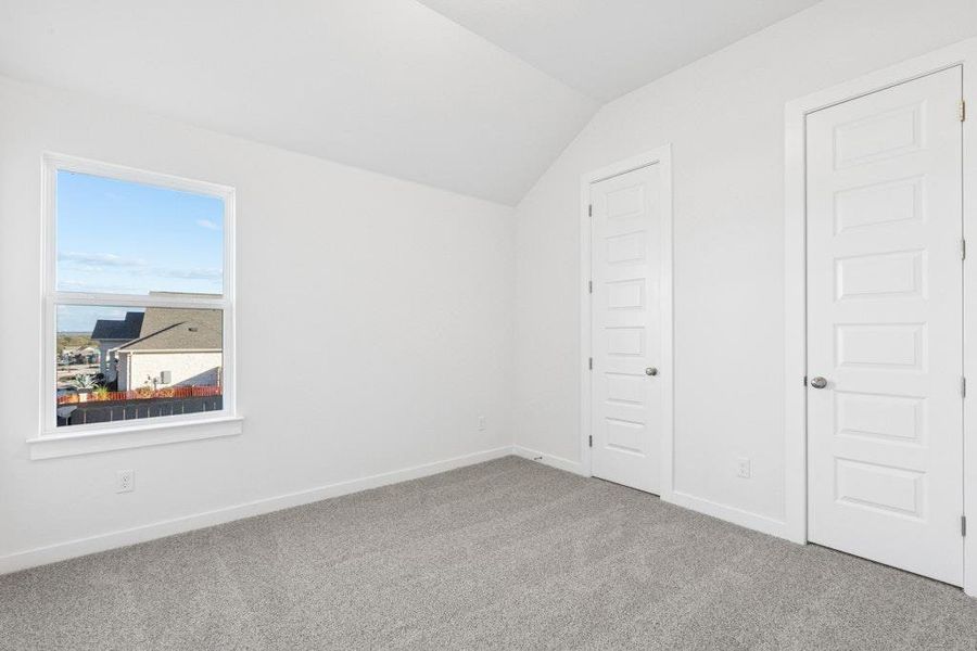 Unfurnished bedroom with vaulted ceiling and carpet flooring Unfurnished bedroom with vaulted ceiling and carpet flooring