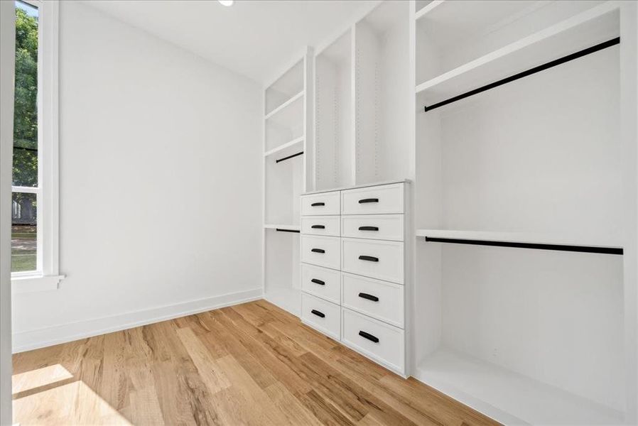 Master closet with light hardwood floors