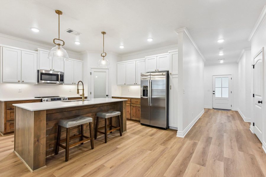 A contemporary kitchen and hallway area features wood flooring and sleek, functional design. A contemporary kitchen and hallway area features wood flooring and sleek, functional design.