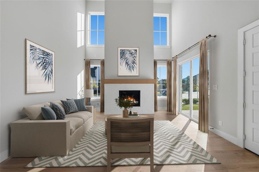 Living area with light wood-style flooring, a high ceiling, and a lit fireplace