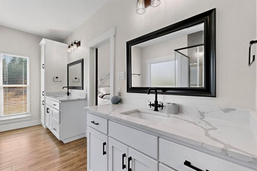 Full bath featuring two vanities, light wood-style floors, and plenty of natural light