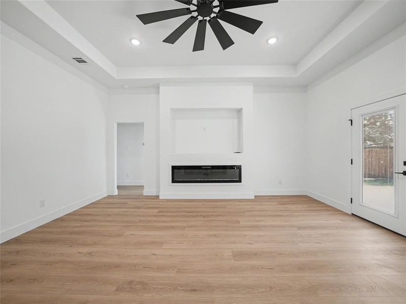 Spacious interior with wood-finish flooring, a built-in electric fireplace, recessed lighting, and a contemporary ceiling fan Spacious interior with wood-finish flooring, a built-in electric fireplace, recessed lighting, and a contemporary ceiling fan