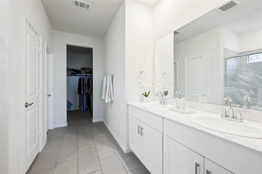 Bathroom featuring a dual vanity with white cabinetry, light-toned countertops, and two undermount sinks Bathroom featuring a dual vanity with white cabinetry, light-toned countertops, and two undermount sinks