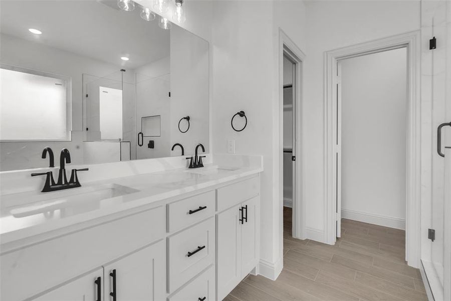 Full bath with a stall shower, double vanity, a spacious closet, wood finished floors, and recessed lighting Full bath with a stall shower, double vanity, a spacious closet, wood finished floors, and recessed lighting