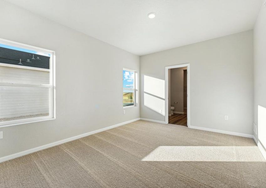 The master bedroom has carpet and two large windows.