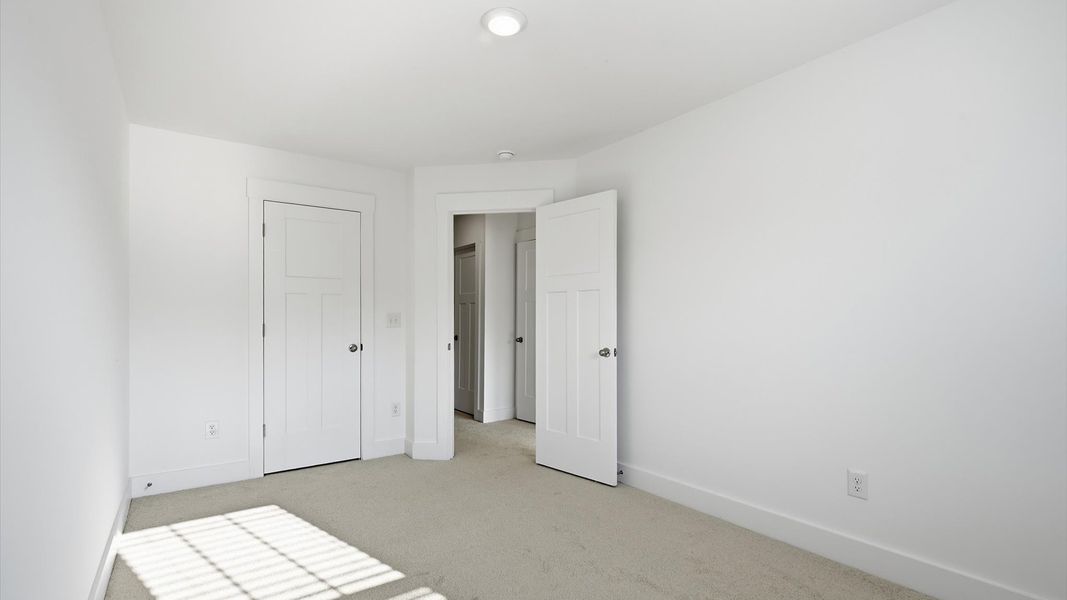 First-rate secondary bedroom with a spacious walk-in closet and elegant carpeted flooring by DRB Homes