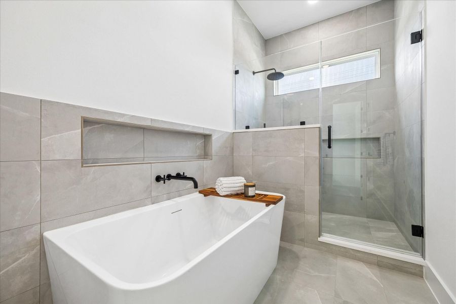 A freestanding soaking tub, frameless glass shower, and full height tile create a serene spa experience.