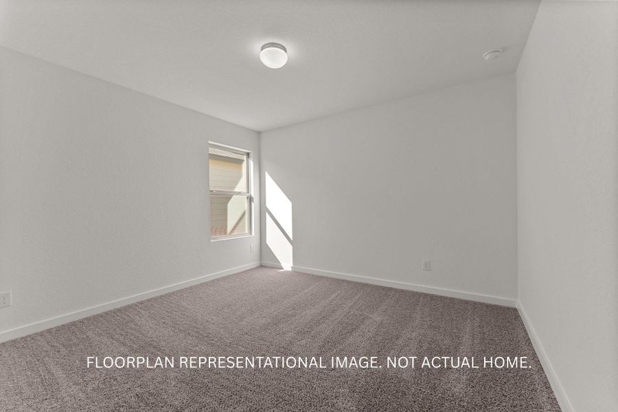 A well-lit bedroom features plush carpeting and a window allowing ample natural light.