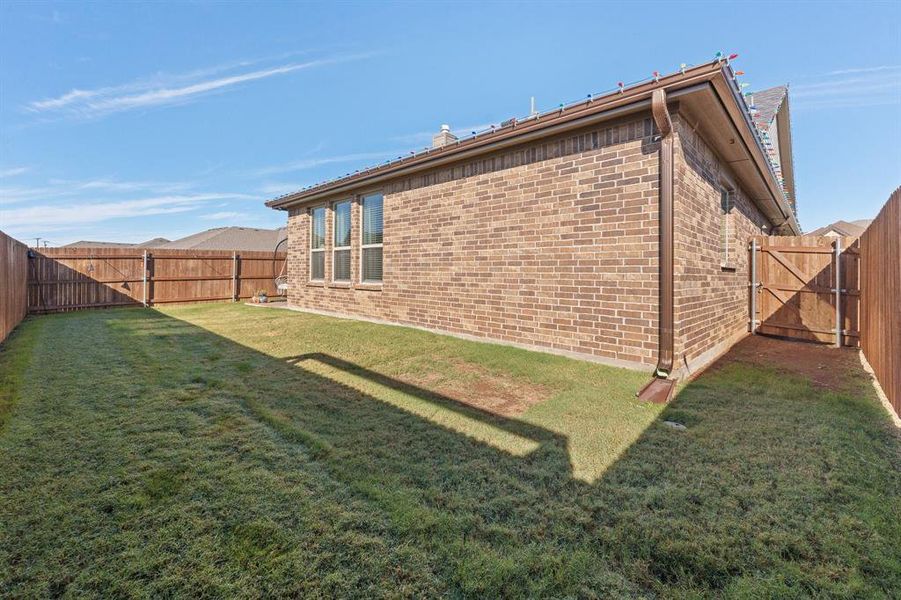 View of side of property with a fenced backyard, brick siding, and a gate