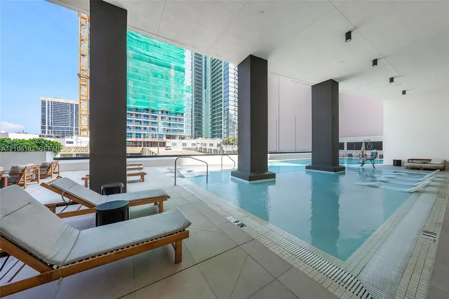 Covered terrace featuring a recessed swimming pool with integrated metal handrails and large-format porcelain tile decking